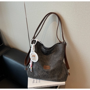 Detail of dark grey canvas tote with brown leather straps and a round Capybara charm