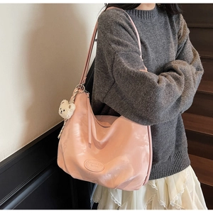 Borsa hobo rosa plissettata con ciondolo a orsetto indossata da una modella in interno