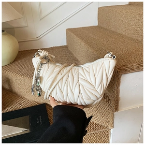 Détail du sac croissant blanc matelassé avec plis délicats et chaîne argentée