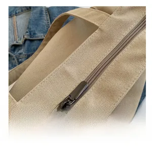 Detail of smooth metal zipper and thick khaki canvas texture on the shoulder tote bag
