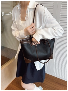 Detail of color-block tote bag featuring black pebble leather and brown braided straps