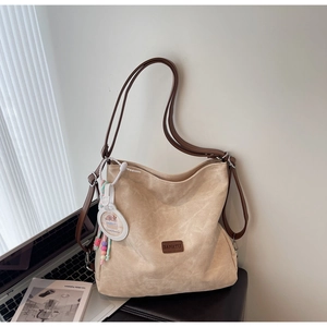 Detail of beige tote bag with brown logo tag and cute Capybara charm hanging on side