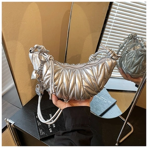 Détail du sac croissant argenté avec poignée nouée et chaîne à pendentif cœur
