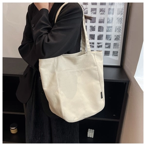 Detailed shoulder view of the spacious cream canvas tote bag with front pocket design