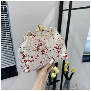 Detailed embroidery of red plum blossoms on a beige satin handbag with pearl buttons