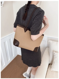 Detail of a khaki patchwork tote bag with woven shoulder straps on a model's shoulder