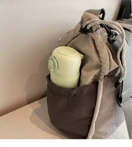 Detail of grey travel bag side elastic pocket holding a small green water bottle