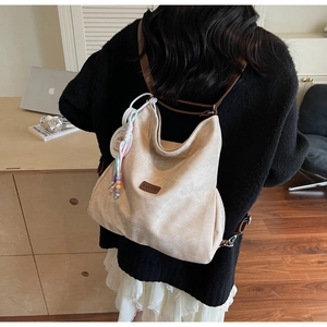 Close-up of cream white hobo backpack with brown leather strap and colorful bead charm