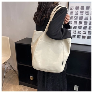 Detail of a large cream tote bag showing soft leather texture and stylish black side label