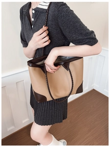 Detail of color-block tote bag featuring brown woven handles and khaki pebble leather