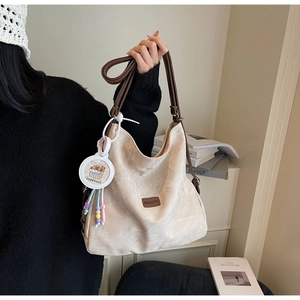 Detailed shot of beige suede tote bag with brown straps and cute Capybara charm
