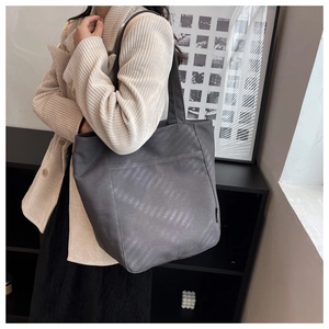 Detail view of a large dark grey tote bag in textured faux leather with shoulder straps