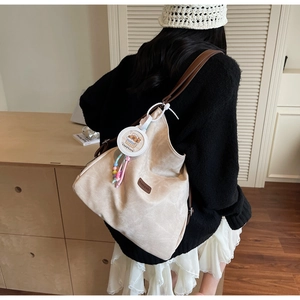 Detail of beige corduroy tote bag featuring a cute capybara charm and brown logo patch