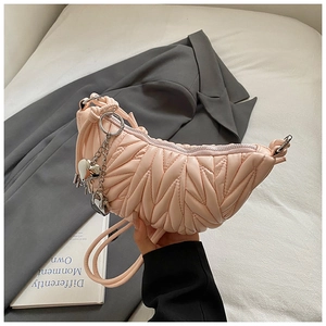Détail du sac croissant rose avec texture matelassée et breloque en forme de cœur