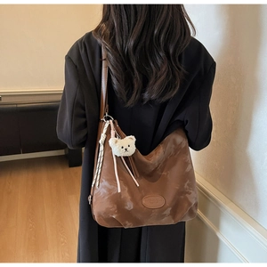 Dettaglio della borsa tote in pelle marrone con ciondolo a forma di orso di peluche bianco