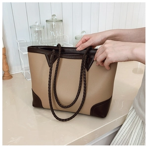 Detail of color-block tote bag featuring contrast leather trim and woven rope handles