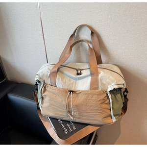 Detail of color-block nylon travel bag showing drawstring pocket and brand lettering