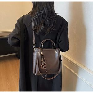 Detail view of a vintage dark brown bucket bag with a stylish pendant and gold hardware
