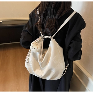 Dettaglio della borsa tote morbida a pieghe color crema con ciondolo a forma di orsetto