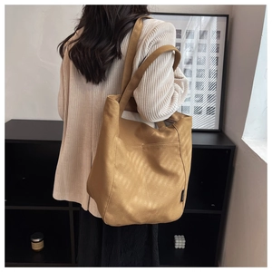 Detail of the camel tote bag with suede texture and brand label shown on model