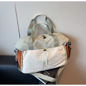 Detail of a large waterproof nylon travel bag with color-block design and adjustable strap