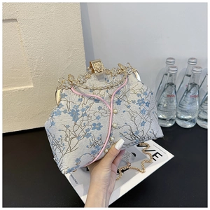 Detail of blue satin qipao style evening bag with floral embroidery and pearl buttons