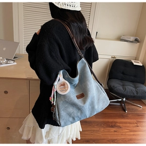 Detail of retro blue-grey canvas tote bag with leather straps and cute mascot pendant