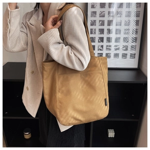 Close-up of the large camel canvas tote bag showing the textured side label and stitching