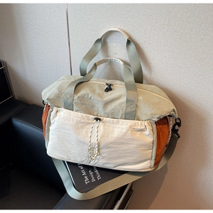Detail of multi-color nylon travel bag showing front drawstring pocket and soft texture