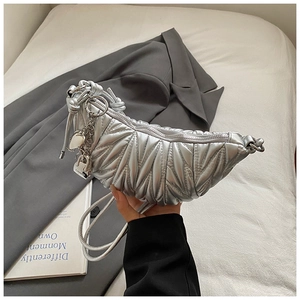 Détail du sac croissant argenté avec coutures plissées, breloque cœur et chaîne