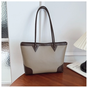 Detail of woven leather handles and two-tone stitching on a large commute tote bag