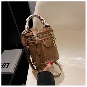 Détail d'un sac seau marron avec poignée en foulard léopard et détails dorés