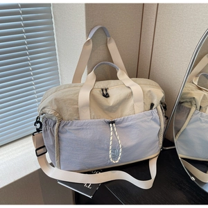 Detail of expandable duffel bag in beige and blue with drawstring front pocket