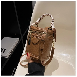 Détail du sac seau marron montrant la texture plissée, foulard léopard et clous dorés