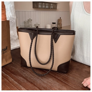 Close-up of color-block tote bag featuring woven leather handles and pebbled texture