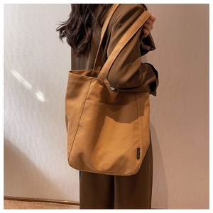Side view of camel canvas tote bag showing the deep capacity and outer pocket detail