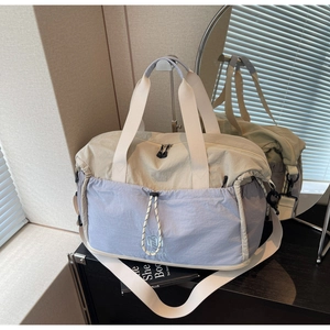 Close-up of beige and light blue travel bag with drawstring pocket and sturdy shoulder strap