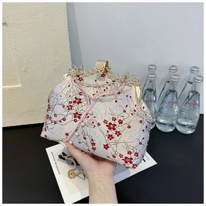 Detailed embroidery of red plum blossoms and pearls on a white satin cheongsam handbag