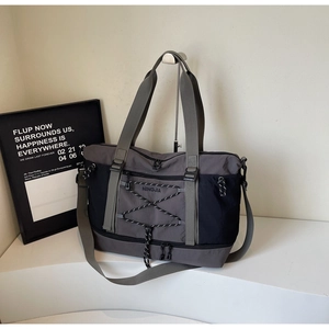 Détail du sac de voyage avec cordons élastiques et bandoulière amovible sur un support chic