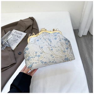 Close-up of vintage floral embroidery fabric and gold metal clasp on a crossbody bag