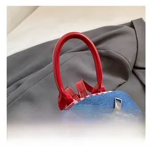 Detailed view of blue denim backpack with red glossy handle and double metal zippers
