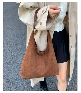 Detail of caramel brown matte suede hobo bag styled with a minimalist autumn trench coat