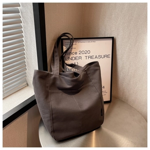 Detail of canvas tote bag with front pocket and decorative seam on a metal table