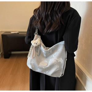 Dettaglio della borsa a pieghe in marmo argento con accessorio ciondolo orso bianco
