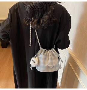 Detail der karierten Beuteltasche mit Kettenriemen und Plüsch-Anhänger am Blazer