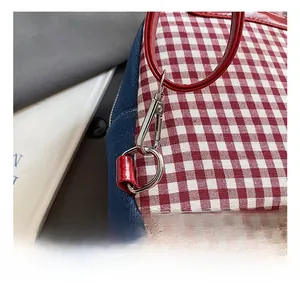 Detail of red gingham and denim backpack with silver metal hook and glossy handle