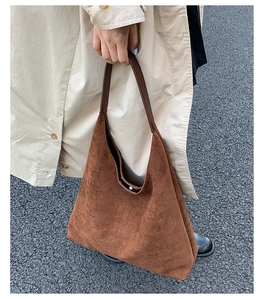 Detailed street style view of a brown suede hobo bag with a dark leather handle and soft texture
