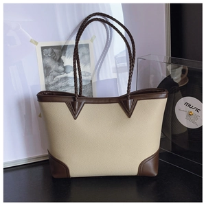 Detail of contrast stitching, woven handle, and lychee grain leather on a large tote bag