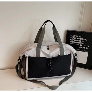 Close-up of a tricolor nylon travel bag with drawstring pocket and adjustable shoulder strap
