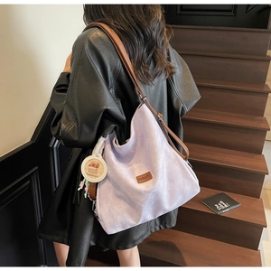 Detail of lavender tote bag featuring a brown leather strap and cute capybara charm